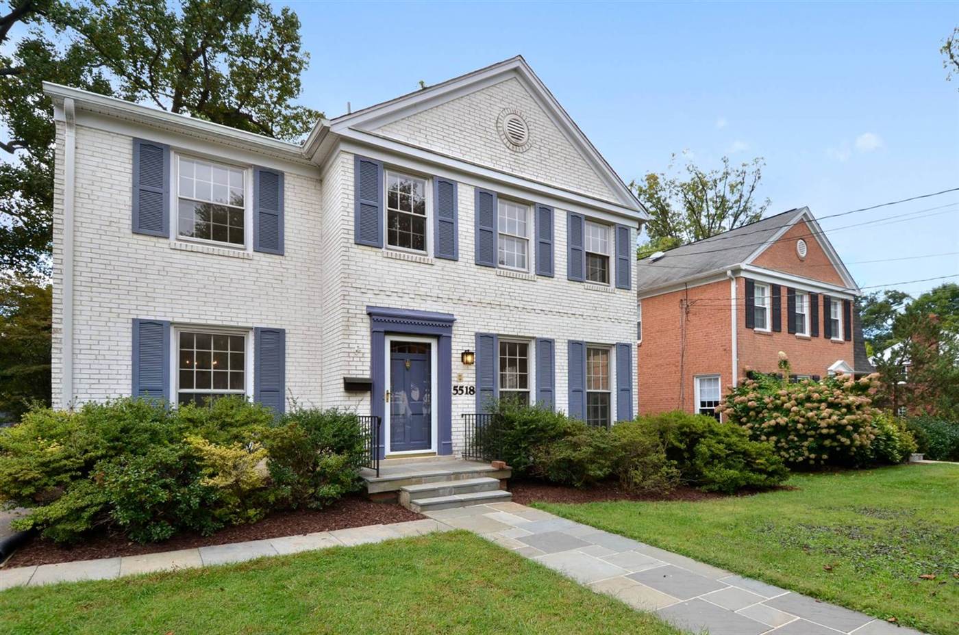 White brick colonial home with blue shutters, side view